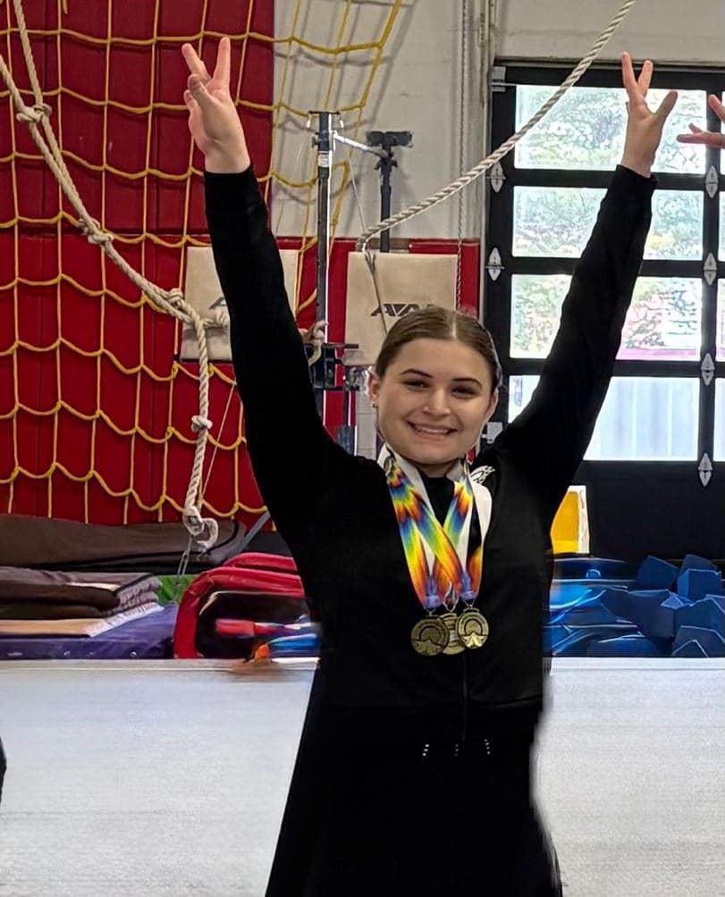 A gymnast saluting, medals around the neck